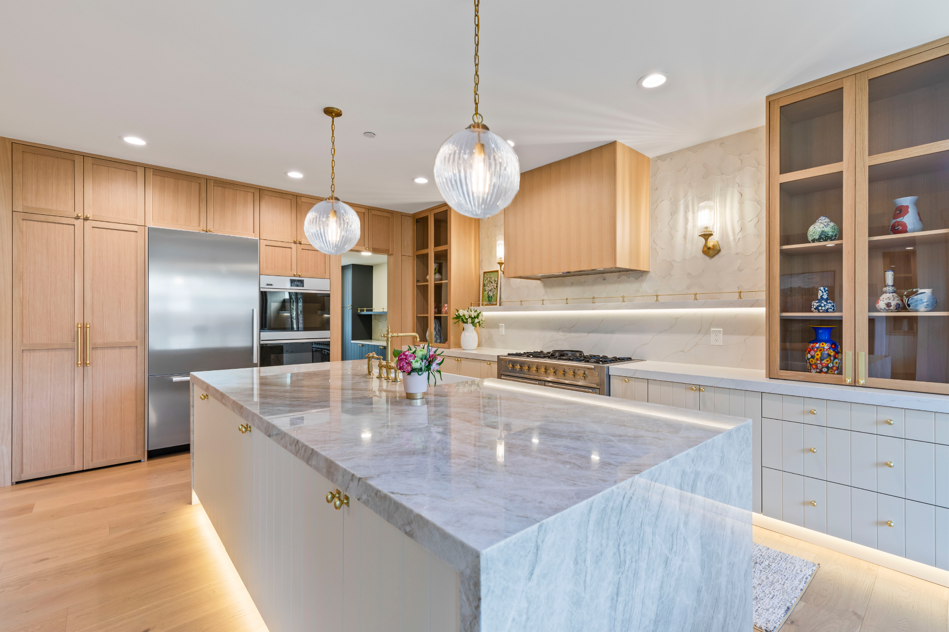 Renovated Edmonds, WA kitchen by Brynn Home Design with a quartzite island, cream cabinetry, unlacquered brass fixtures and ribbed glass pendant lights
